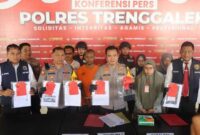 Kapolres Trenggalek, AKBP Gathut Sunu Sipriyono (tengah) menunjukkan barang bukti penipuan berkedok jual beli mobil berikut tersangkanya, di Mapolres Trenggalek