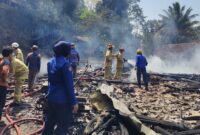 Petugas gabungan berusaha memadamkan api ditengah puing-puing bangunan rumah yang terbakar api.