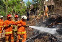 Tim Pemadam Kebakaran Trenggalek berusaha memadamkan api yang menjalar ke kandang kambing.