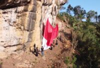Upacara dilakukan pemanjat profesional sebelum mengibarkan bendera raksasa di tebing Belik Bolu, di Desa Jajar, Kecamatan Gandusari, Kabupaten Trenggalek.