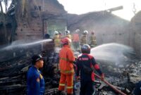 Petugas pemadaman kebakaran berusaha memadamkan api gudang toko oleh-oleh di Dusun Kranding, Desa Bendorejo, Kecamatan Pogalan, Trenggalek.