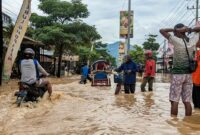 Masyarakat berusaha menerjang banjir di jalan Nasional Trenggalek-Tulungagung masuk wilayah Kelurahan Kelutan.