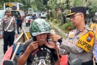 Kapolres Trenggalek, AKBP Ridwan Maliki pakaikan helm pada pengendara motor roda dua yang melintas di depan Polres Trenggalek.