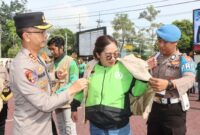 Kapolres Trenggalek, AKBP Ridwan Maliki memakaikan rompi bertuliskan Ojol Kamtibmas usai apel bersama komunitas Ojol Trenggalek.