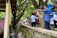 Nampak Ketua Komisi II DPRD Trenggalek Mugianto menunjuk ke arah sesuatu bangunan di parkiran Pantai Karanggongso.