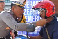 Kasatlantas Polres Trenggalek AKP Sony Suhartanto pakaikan helm pada pengendara saat Operasi Zebra Semeru 2025 di seputaran Pasar Pon Trenggalek, Rabu (19/11/2025).