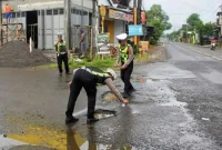 Satlantas Polres Trenggalek petakan dan tandai jalan berlubang dengan cat warna putih fosfor agar nampak saat tertutup genangan air.
