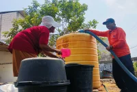 Petugas BPBD Trenggalek menyalurkan bantuan air bersih kepada warga Desa Sambirejo saat musim kemarau.