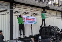 Anggota Ansor-Banser memasang spanduk bertuliskan penolakan penjualan minuman keras di depan gerai miras di Trenggalek.
