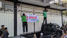 Anggota Ansor-Banser memasang spanduk bertuliskan penolakan penjualan minuman keras di depan gerai miras di Trenggalek.