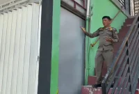 Petugas Satpol PPK Trenggalek memeriksa kondisi pintu gerai miras Sari Jaya di Ruko Jaas, Trenggalek, setelah segel penyegelan ditemukan rusak.